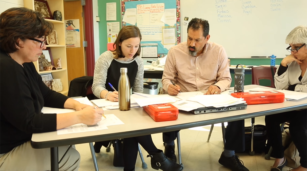 Four educators working at a Chicago Public School classroom table, working on papers, through Loyola's Center for Science and Math Education.