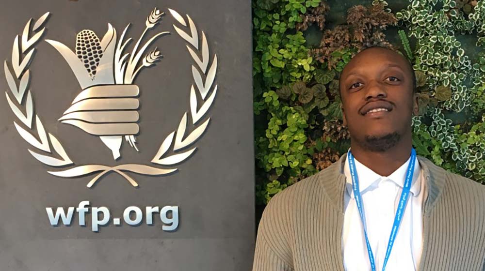 Saidi Mwanundu in front of WFP sign