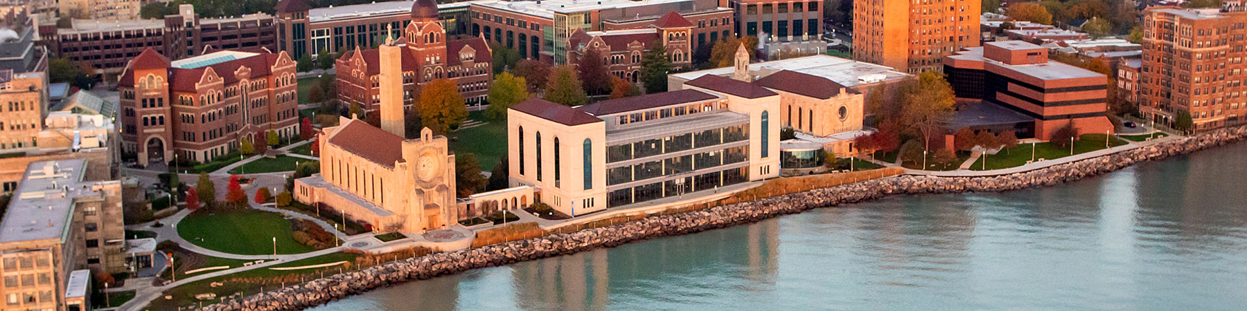 An aerial view of Loyola University Chicago's Lake Shore Campus from lakeside with beautiful cumulus clouds in the sky