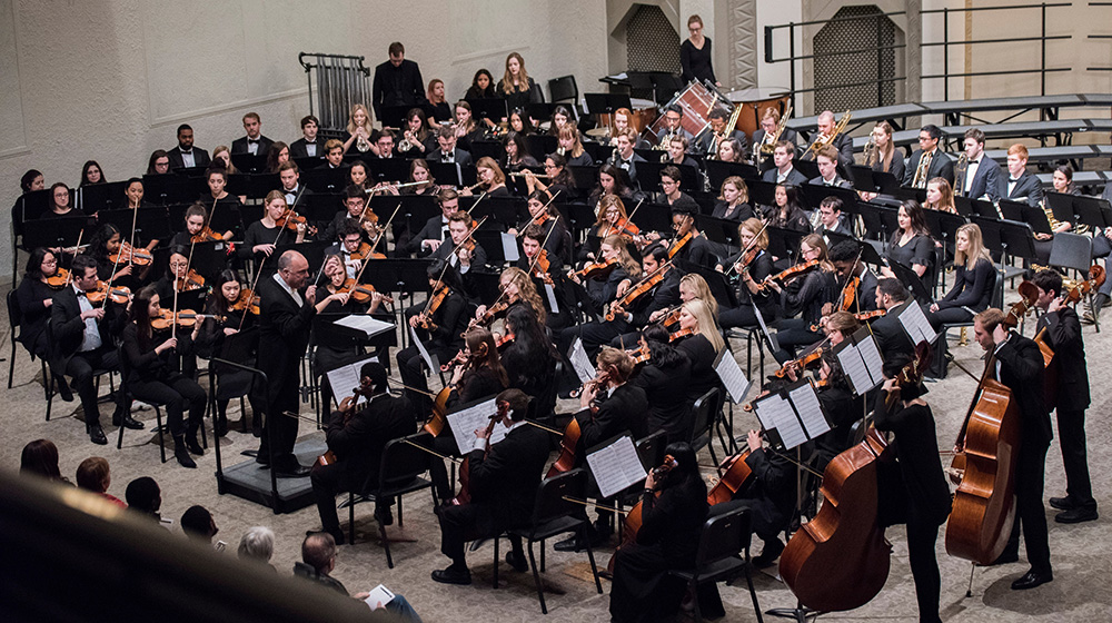 An orchestra performs on stage in Rooney Hall at Loyola University Chicago. An orchestra performs on stage in Rooney Hall at Loyola University Chicago.