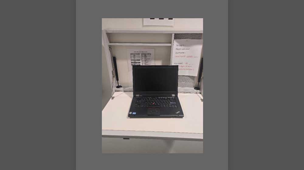 Laptop computer on drop-down desk outside of room Laptop computer on drop-down desk outside of room