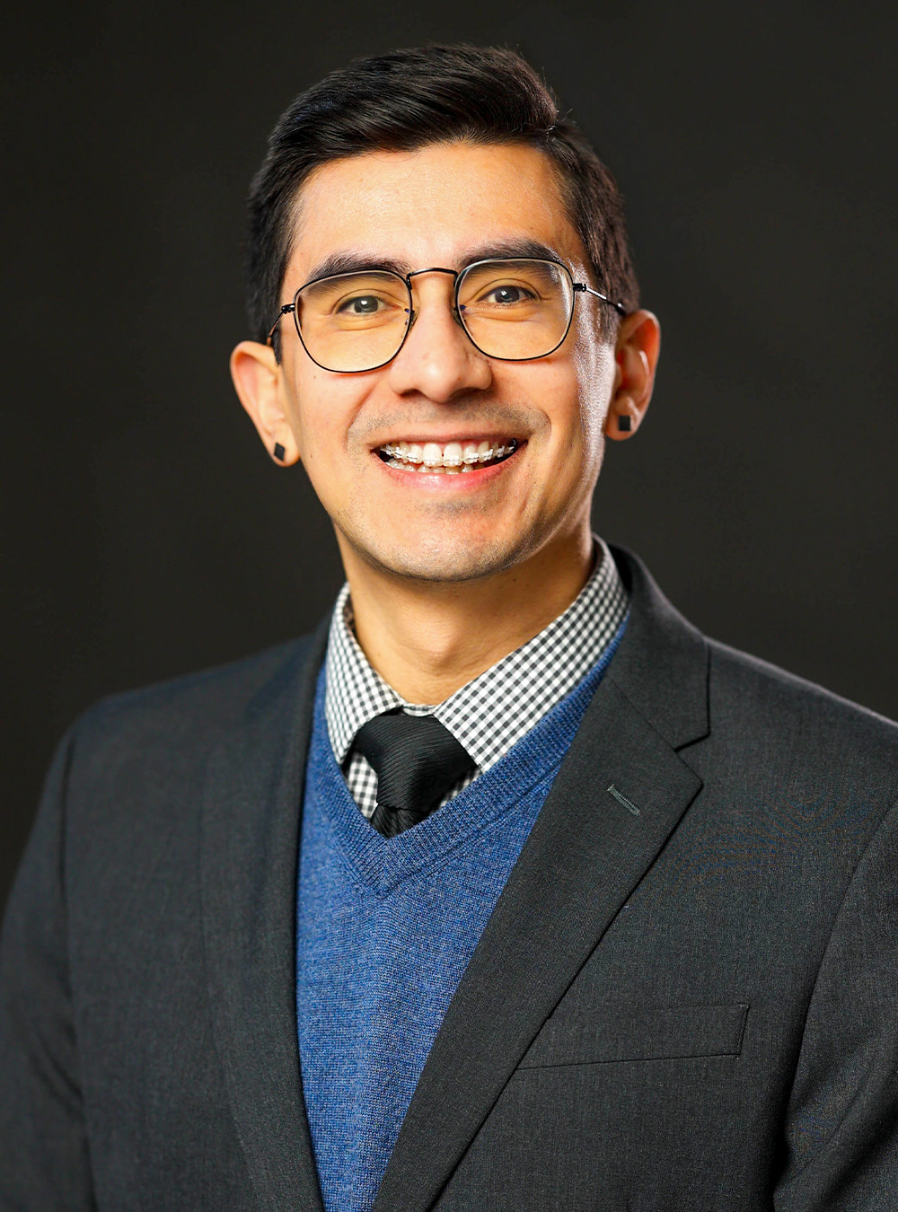 Portrait of a smiling man wearing glasses and a suit against a dark background Portrait of a smiling man wearing glasses and a suit against a dark background