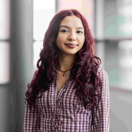 Arrupe student with long burgundy hair posing outside brick building