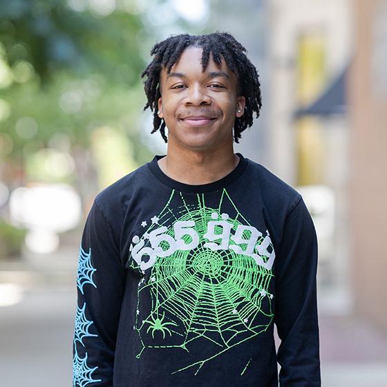 Portrait of a smiling student wearing a black graphic sweatshirt on Loyola University Chicago’s campus.