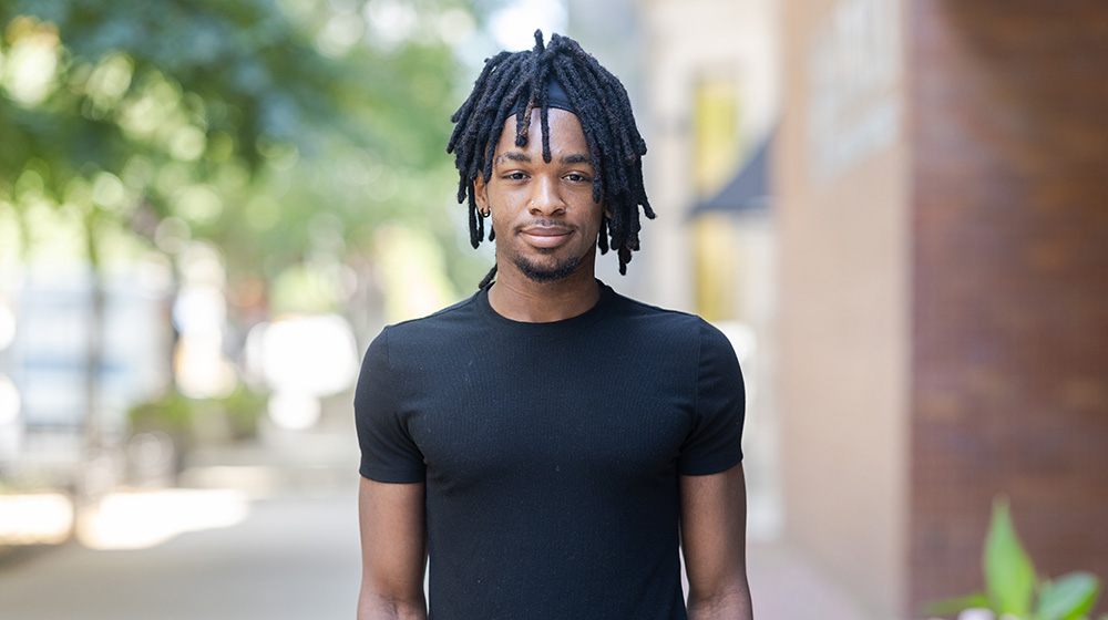 Portrait of a student standing outdoors on Loyola University Chicago’s campus with trees and buildings in the background.