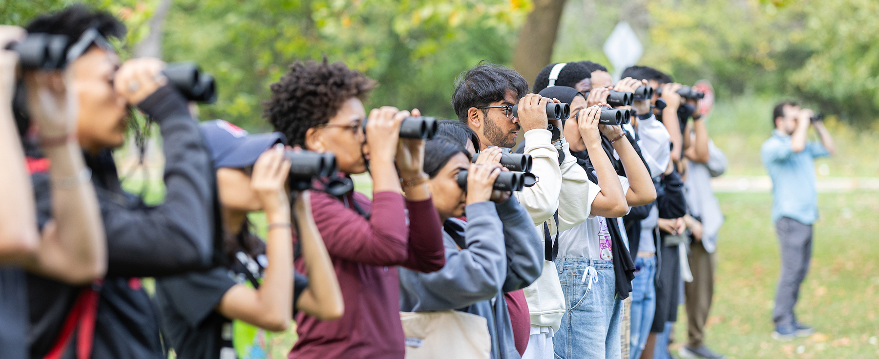 Students using spotting scopes and binoculars during a science field trip