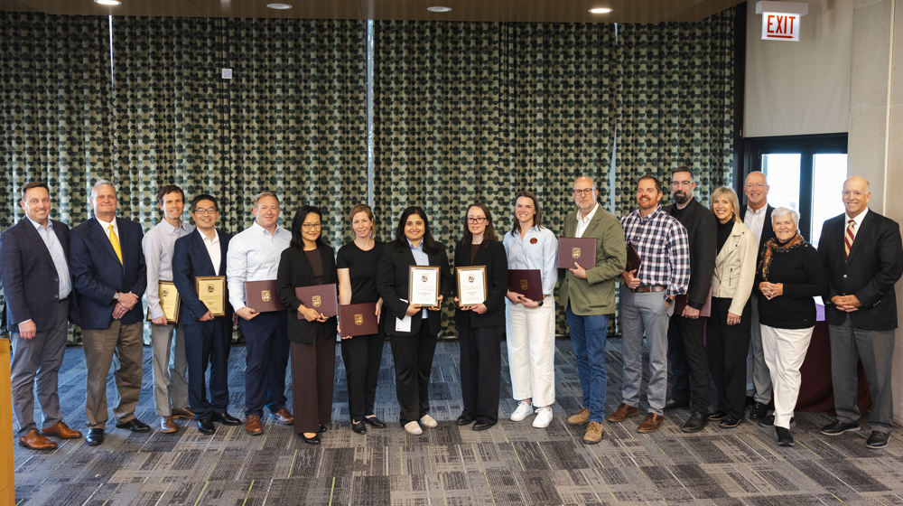 Faculty pose for photo with awards