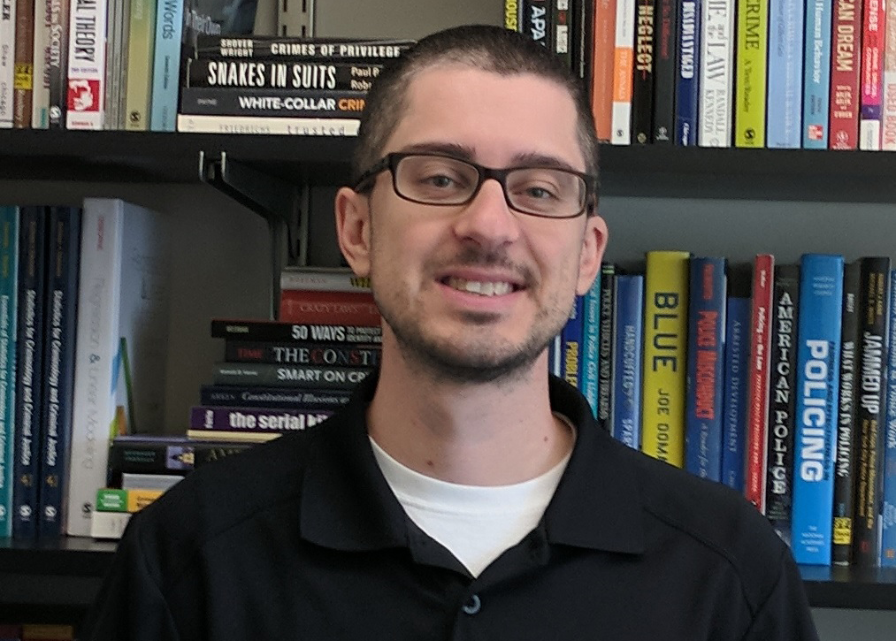 Chris Donner smiles in front of a bookcase