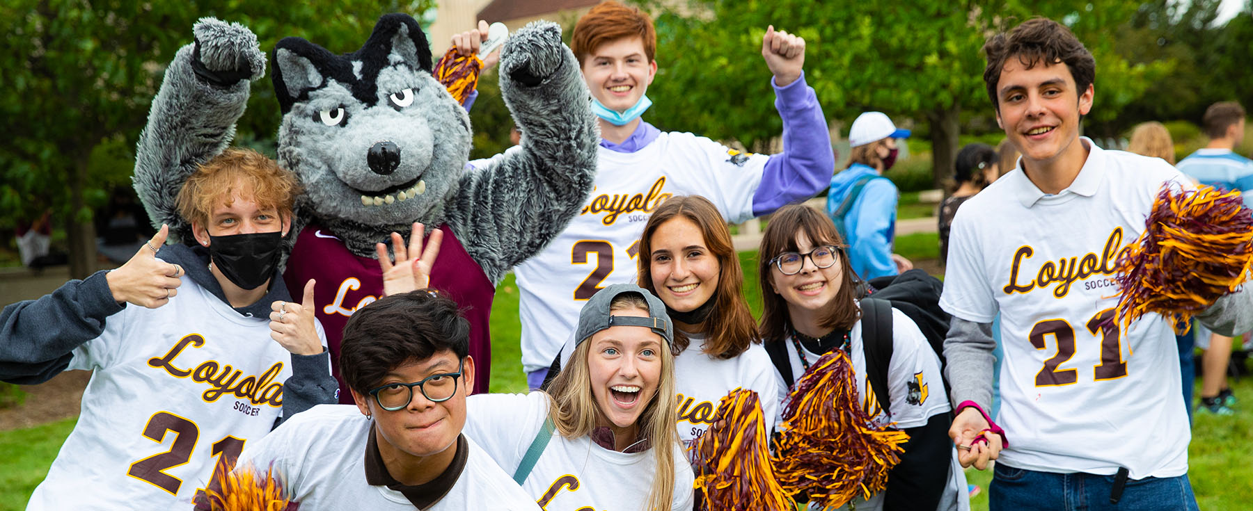 LUC students showing their school spirt while standing next to Lu Wolf