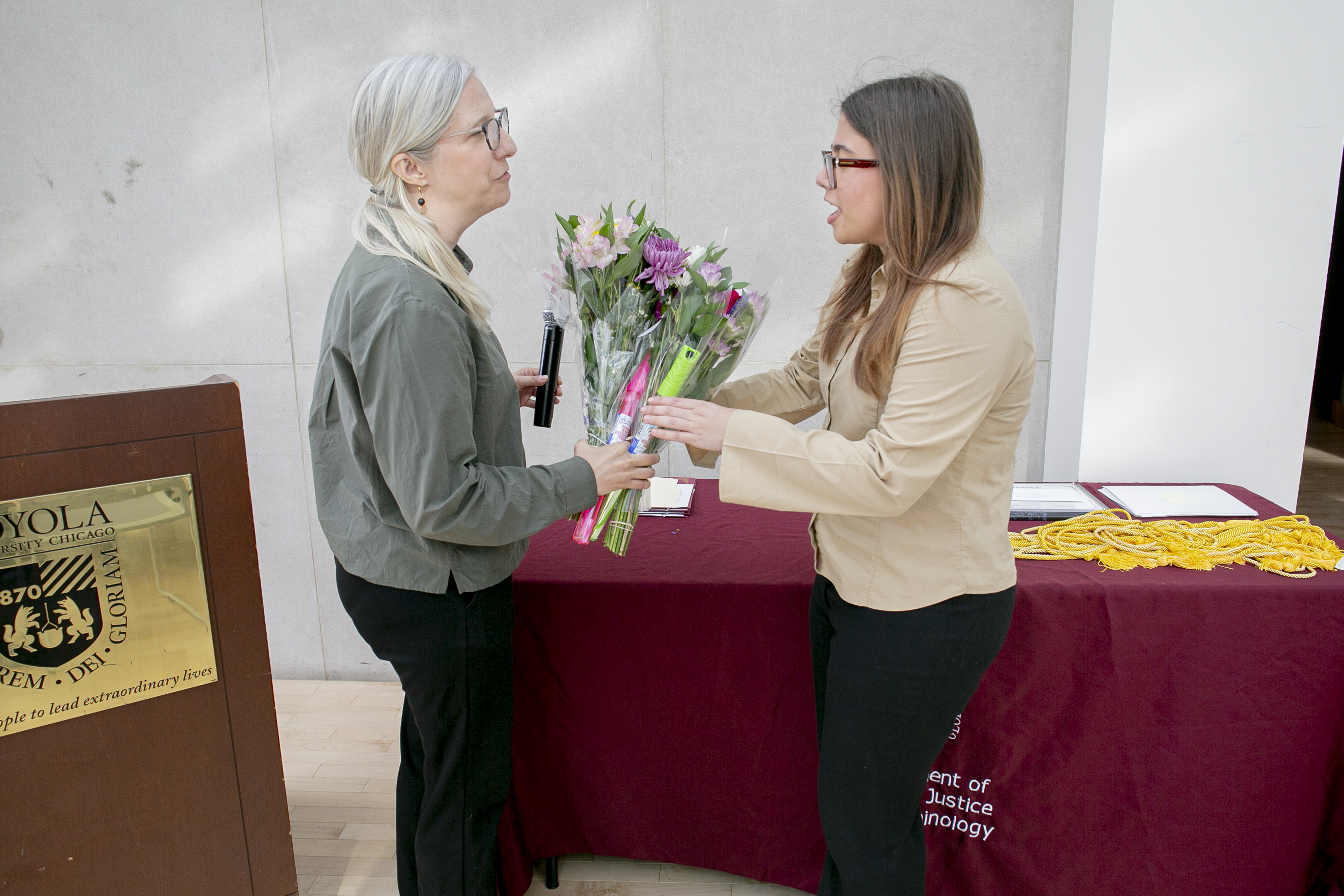 Dr. Webster presenting flowers to a graduating CJO student