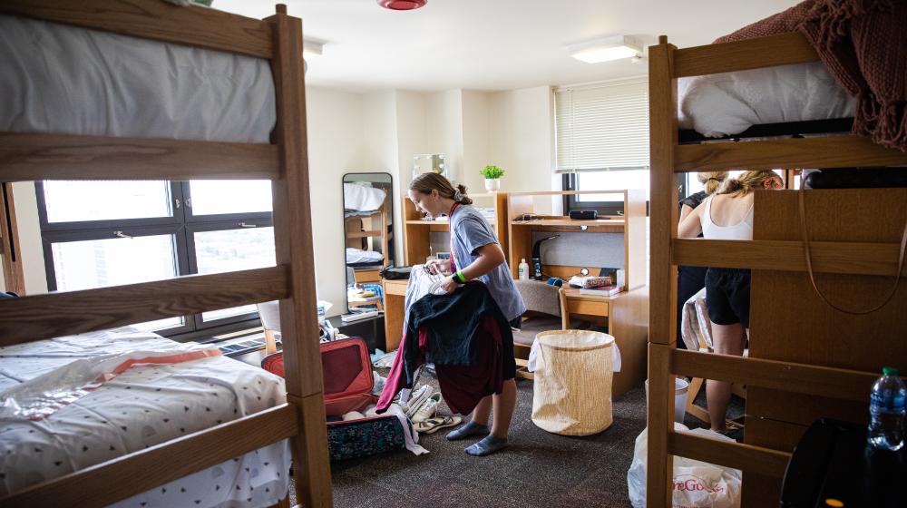 Student sorting clothes in a dormitory room via Loyola University Chicago's housing student resources.