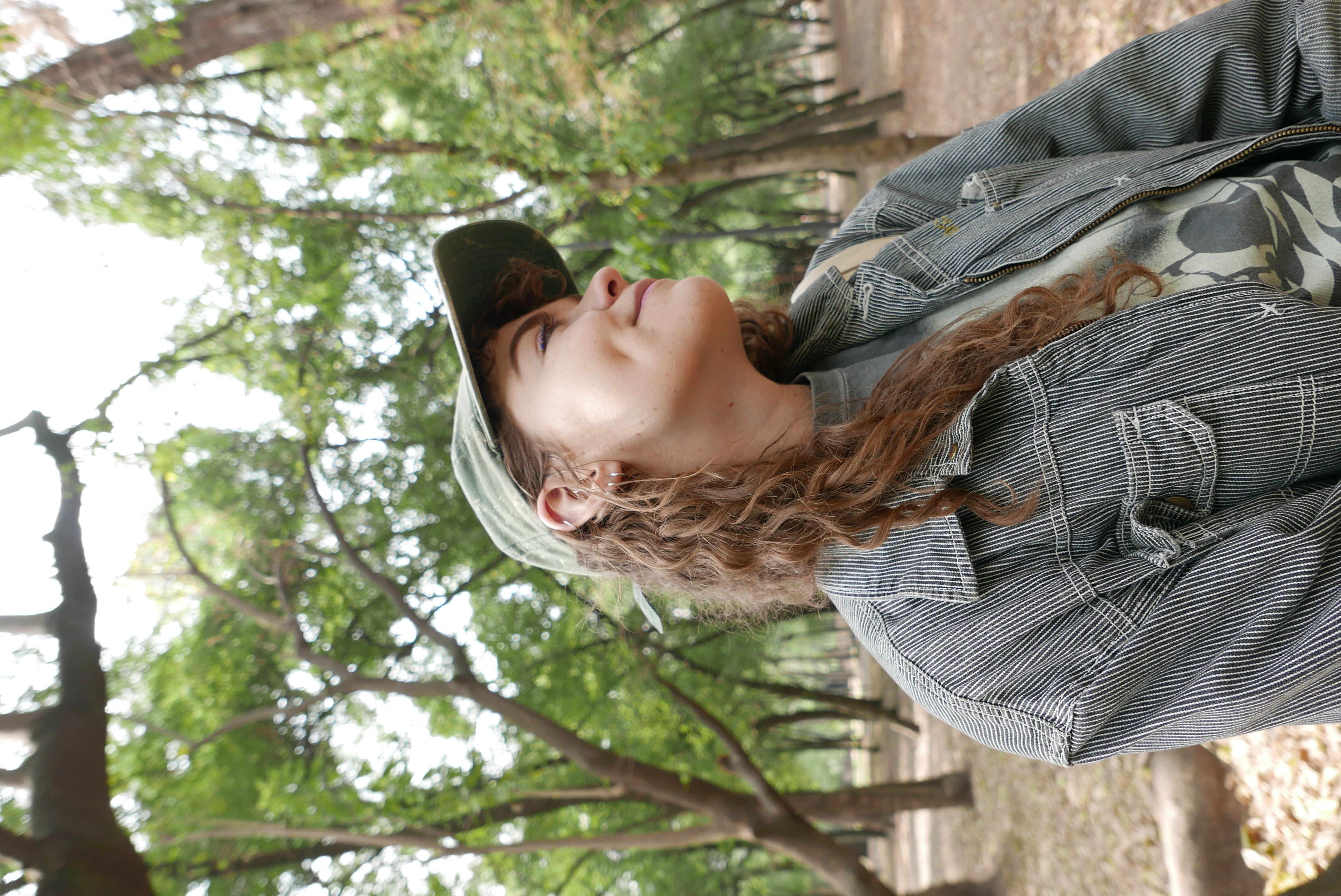Bex standing in a forest with full green trees behind them