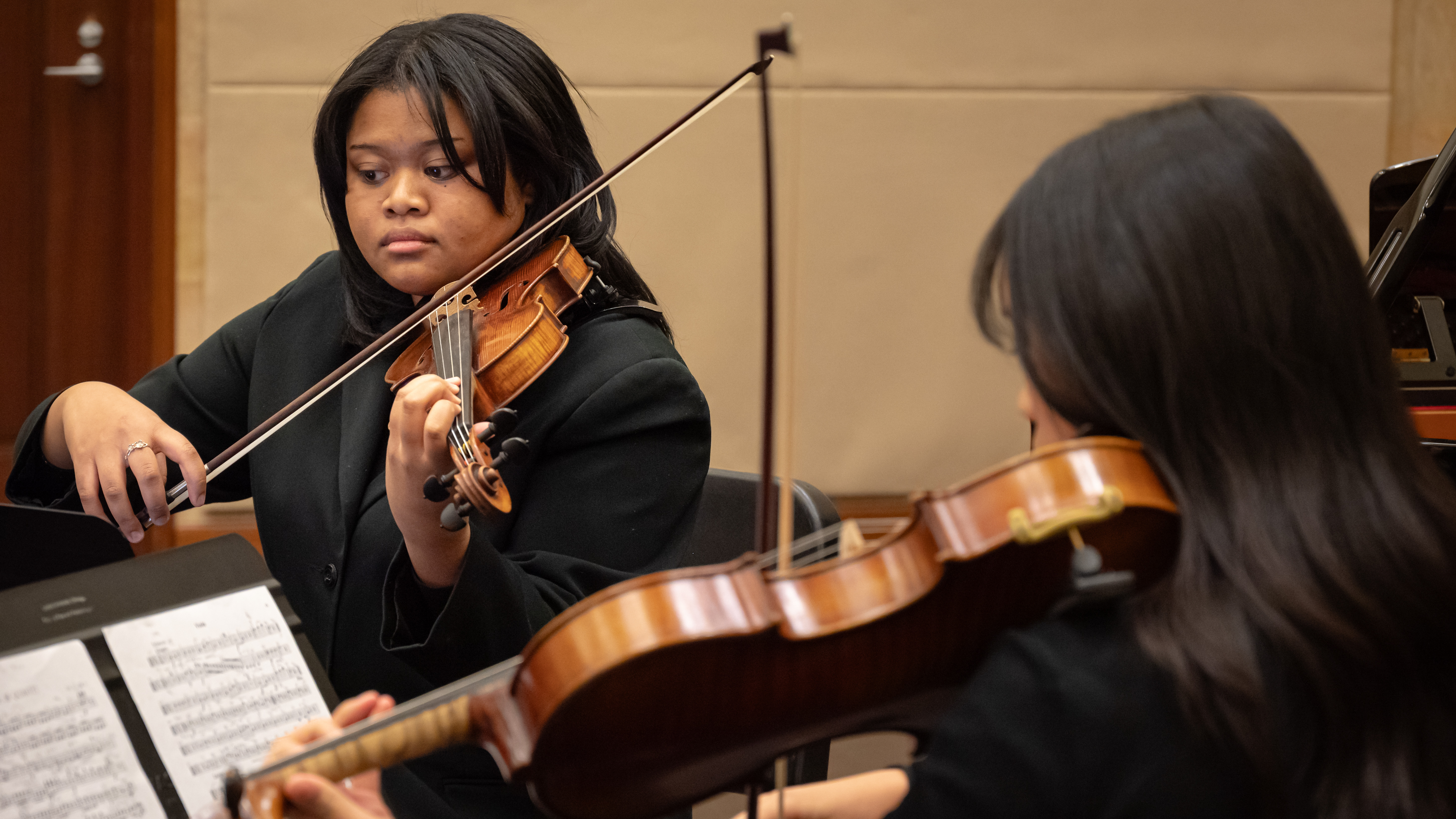 Loyola Chamber Ensemble students playing violins in the music hall Loyola Chamber Ensemble students playing violins in the music hall