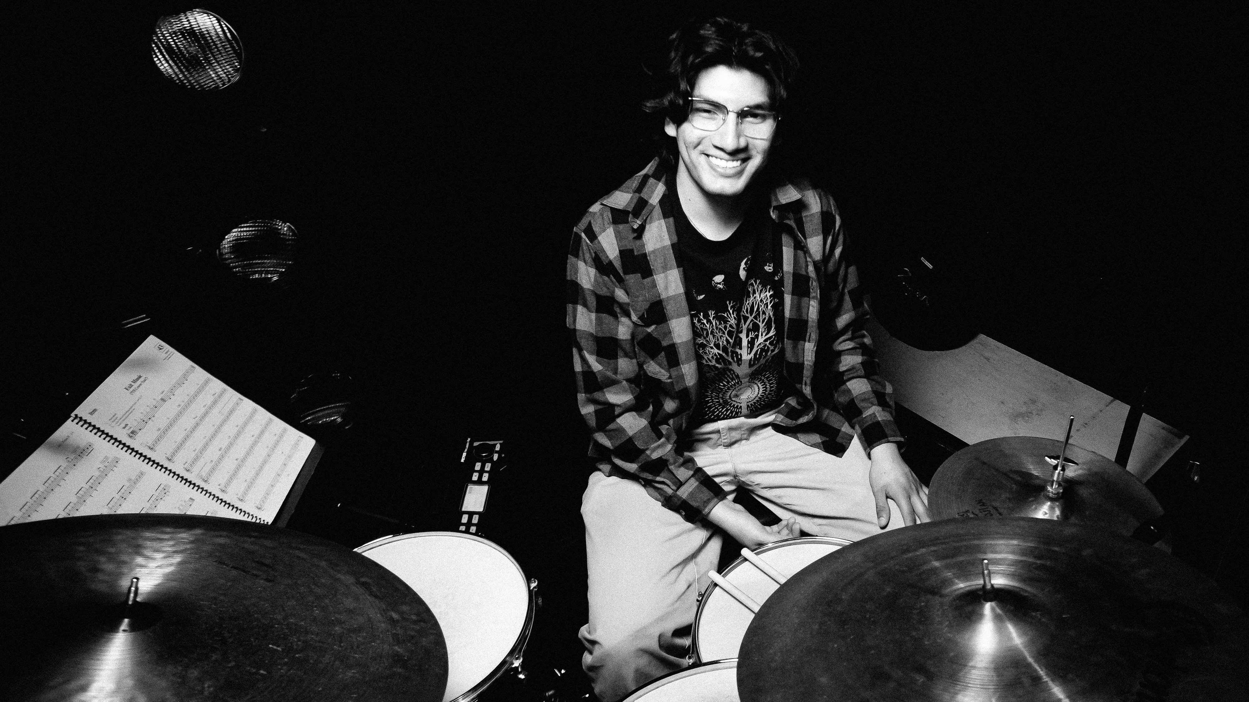 Loyola Music student sitting next to a drum set ready to perform Loyola Music student sitting next to a drum set ready to perform
