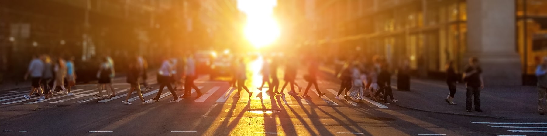 Students use a crosswalk as the sun sets in the background.