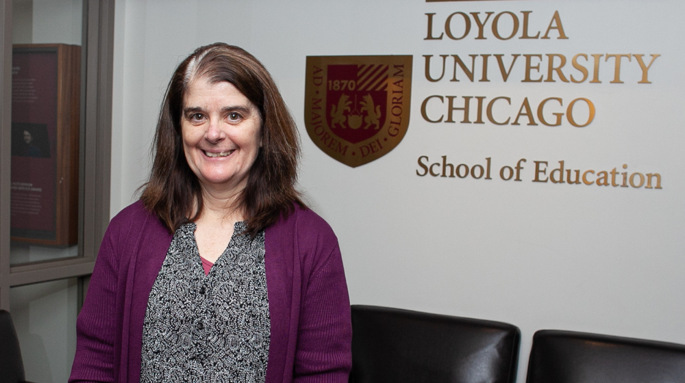 Dr Pam Fenning stands in front of the Loyola School of Education sign