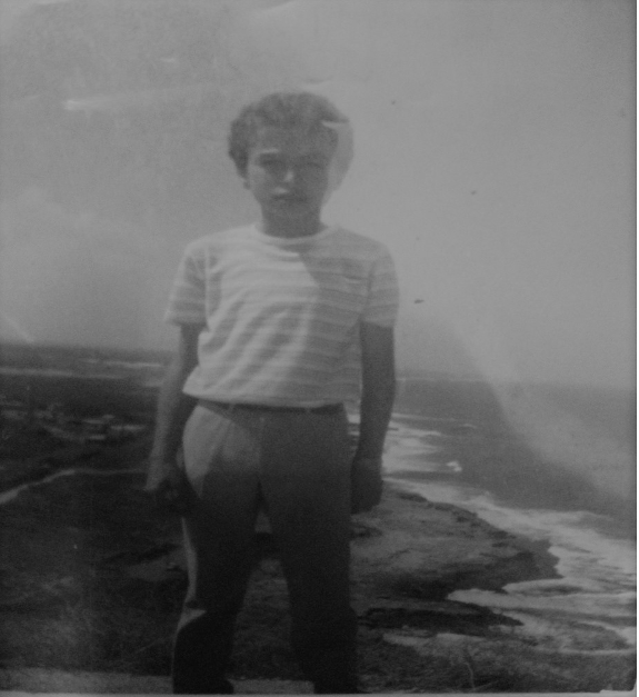 An old, black and white photo of a young boy of about ten years old at a beach An old, black and white photo of a young boy of about ten years old at a beach