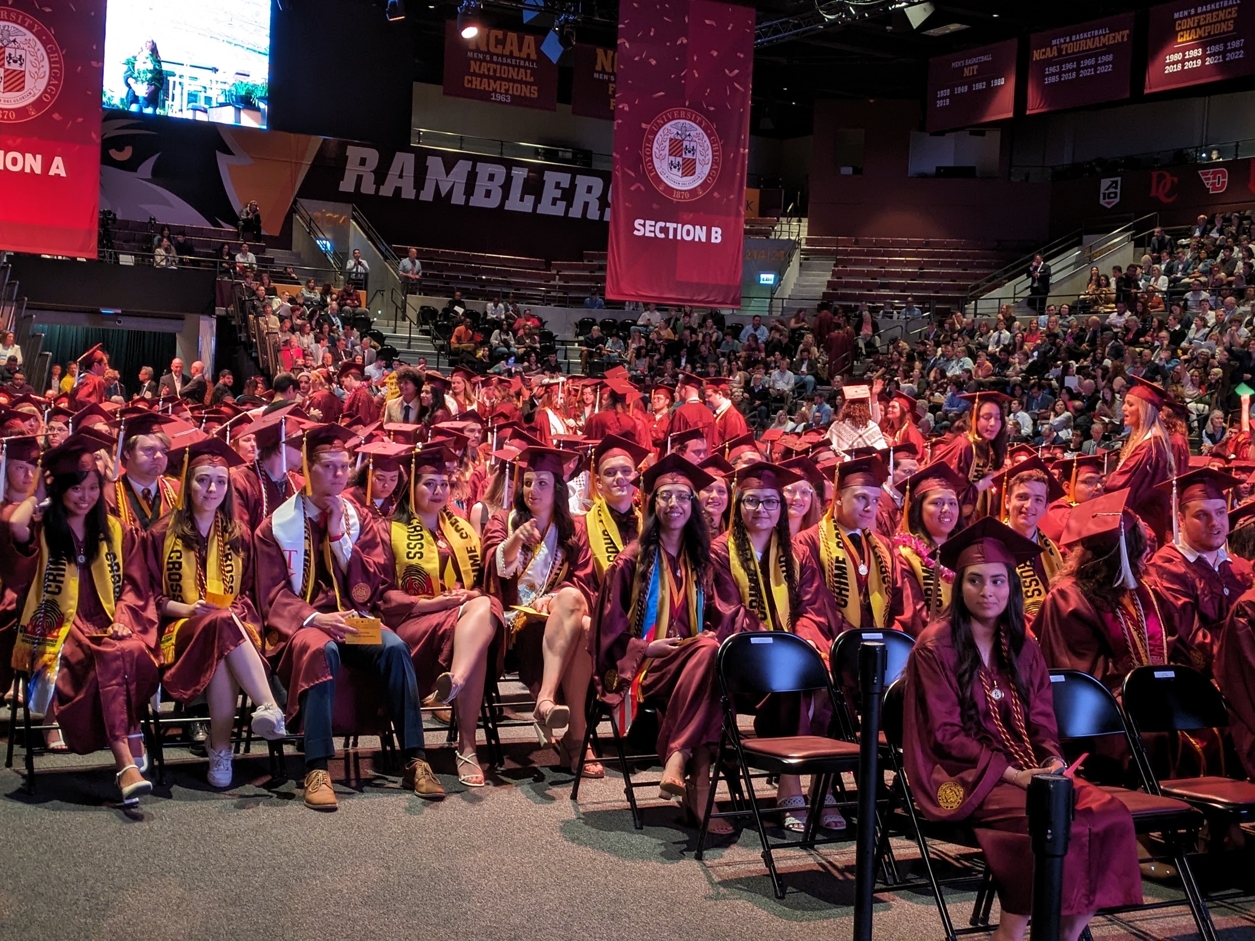 A large group of people gather for a photo in front of a statue. The people are all wearing yellow scarves with writing on them A large group of people gather for a photo in front of a statue. The people are all wearing yellow scarves with writing on them