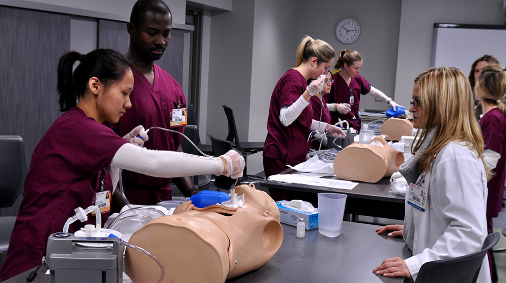Nursing students practice a procedure on a simulation training dummy
