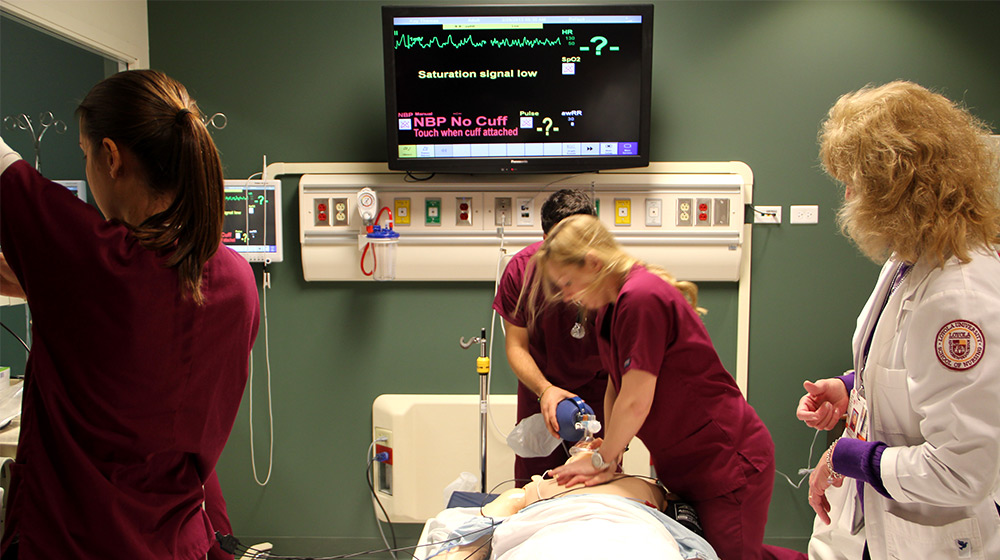 Multiple Loyola medical students practice a procedure on a simulation mannequin