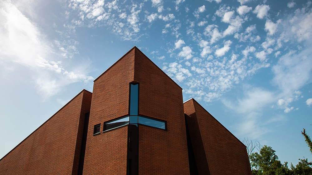 Sky, clouds, and JFRC campus building with a cross for a window