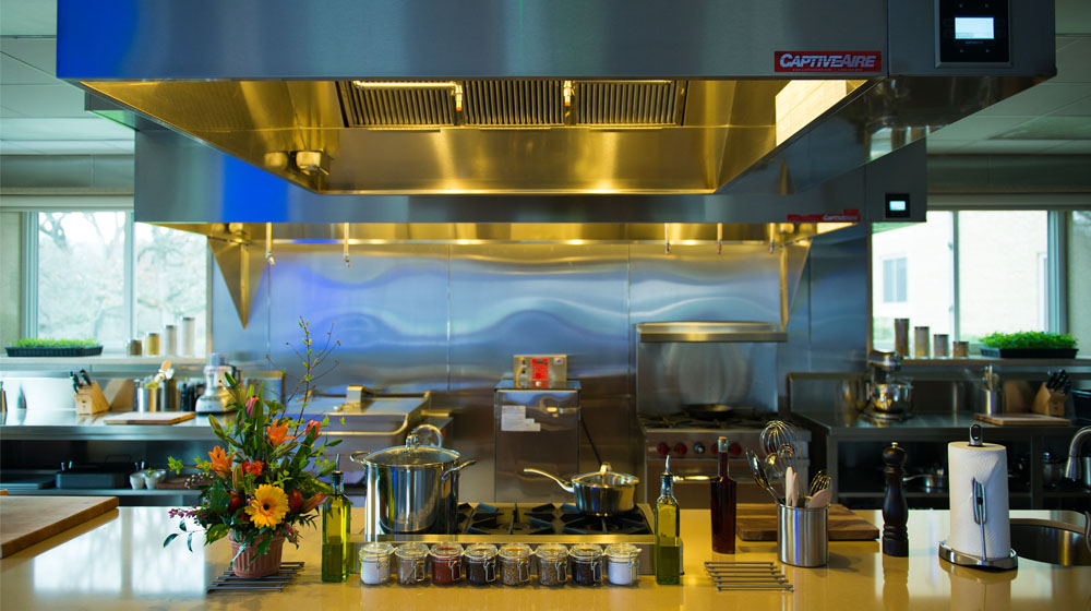 A stainless steel commercial kitchen with multiple ranges and cooking utensils A stainless steel commercial kitchen with multiple ranges and cooking utensils