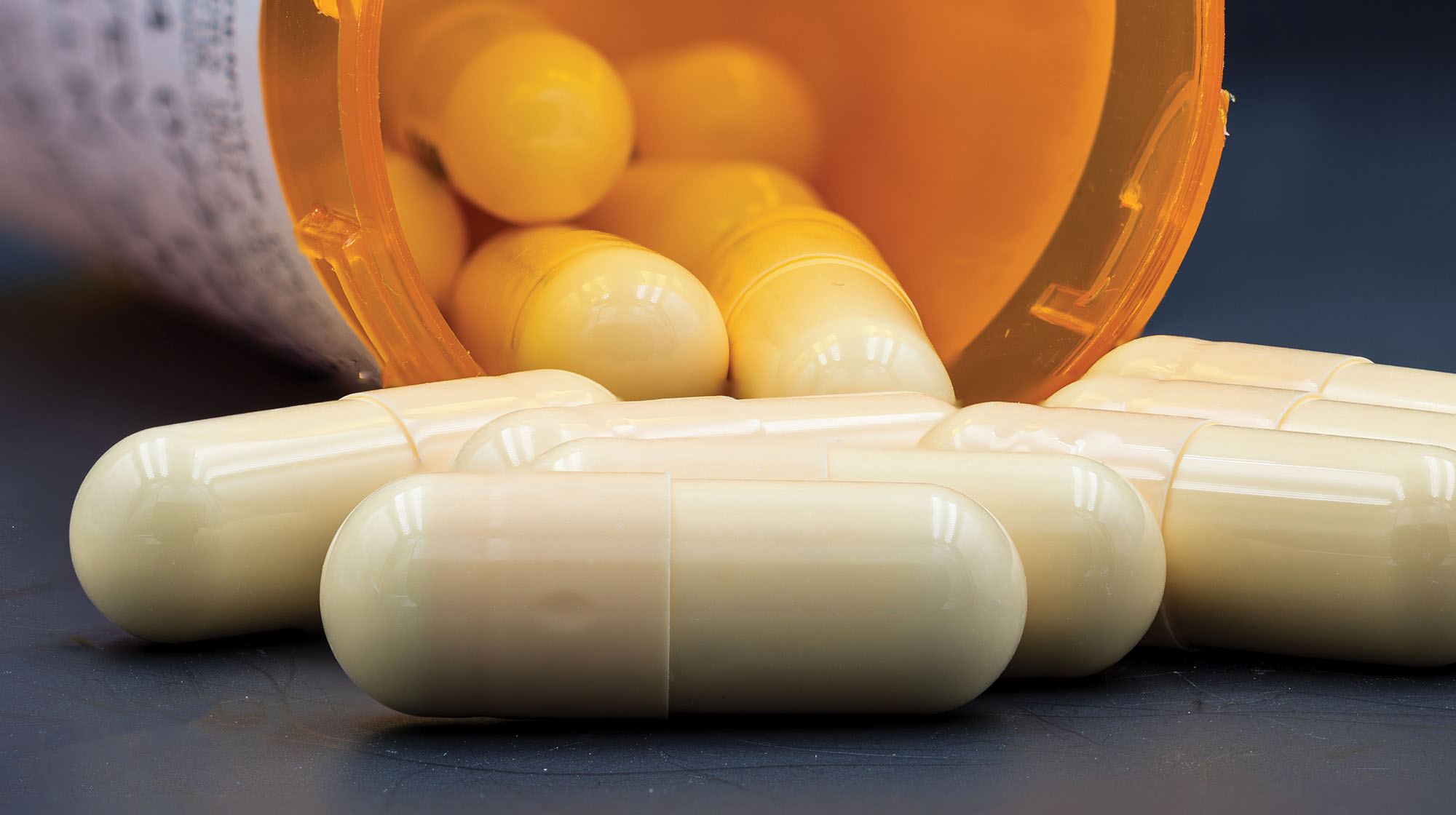Pill capsules in front of a bottle.