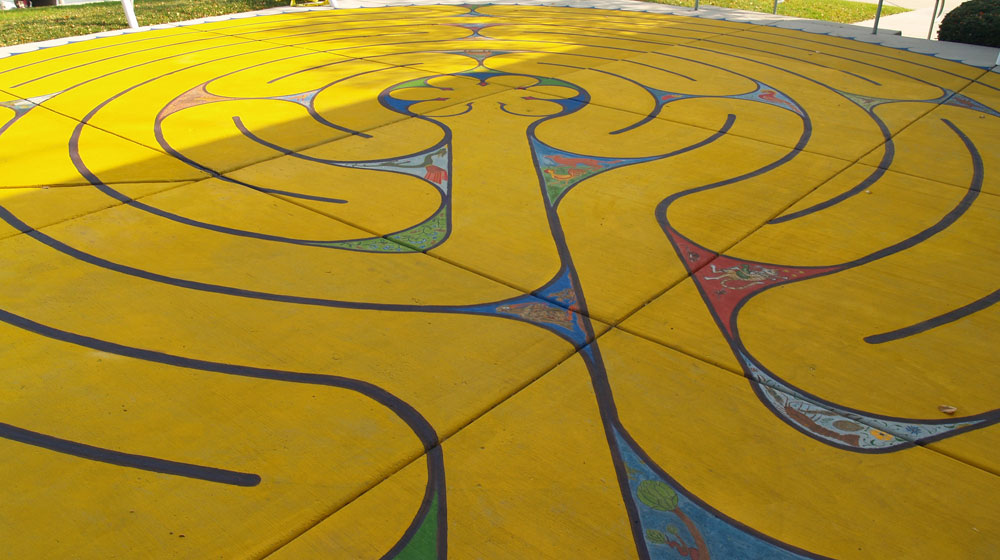 A large mural on the ground outdoors that resembles a winding yellow tube