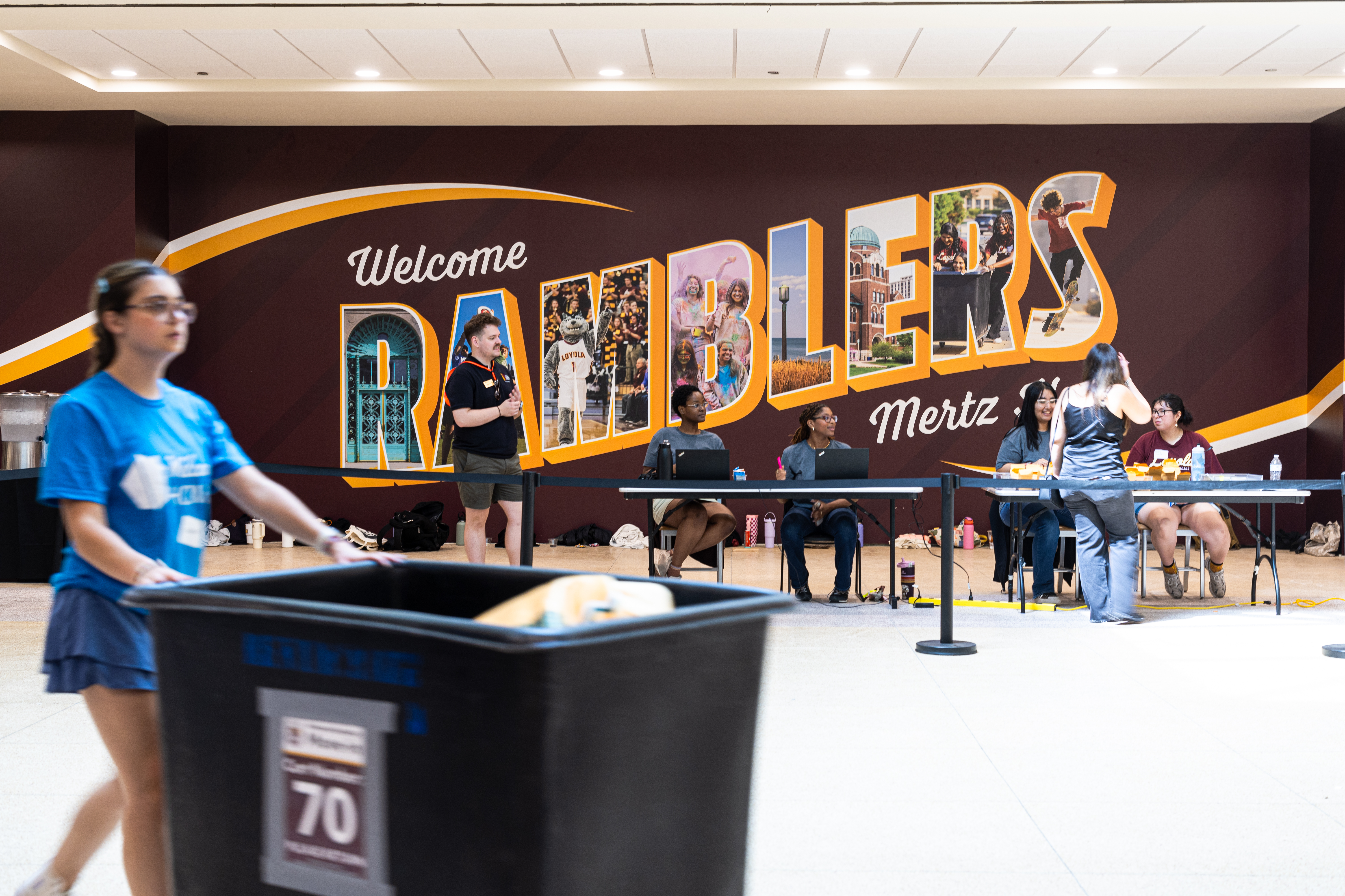 student pushing a cart of personal items with Ramblers imprinted in the background