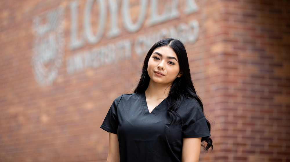 Jessica Martinez stands in her nursing scrubs outside Arrupe College on Loyola's Water Tower Campus
