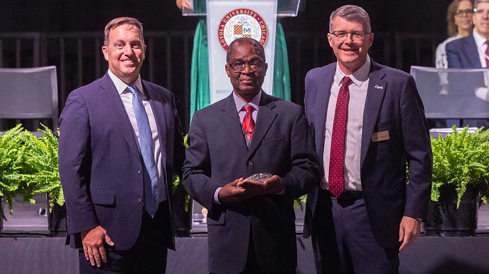 Professor Bamidele Tayo (center) accepts the Pedro Arrupe, S.J., Faculty Award for Diversity Leadership from President Mark C. Reed (left) and Provost Doug Woods (right). Professor Bamidele Tayo (center) accepts the Pedro Arrupe, S.J., Faculty Award for Diversity Leadership from President Mark C. Reed (left) and Provost Doug Woods (right).