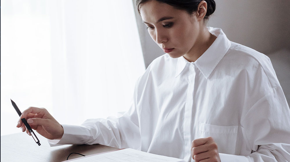 Woman seated at table looking through paperwork.