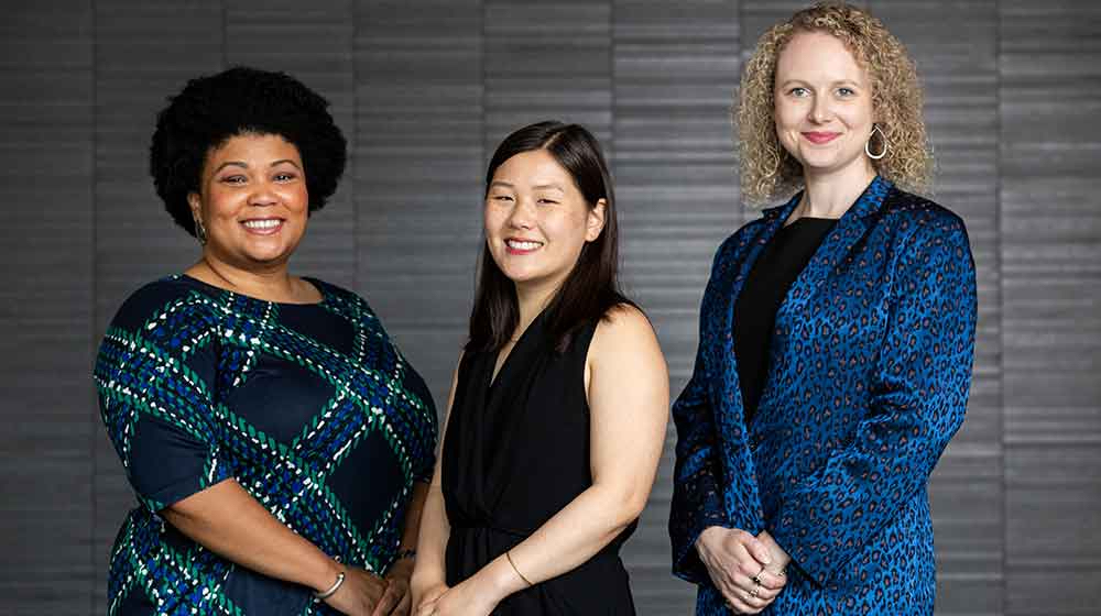 Three Baumhart Center staff standing in front of a stone wall