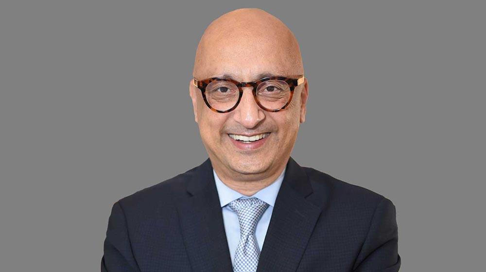 Headshot of Michael Behnam smiling in front of gray background