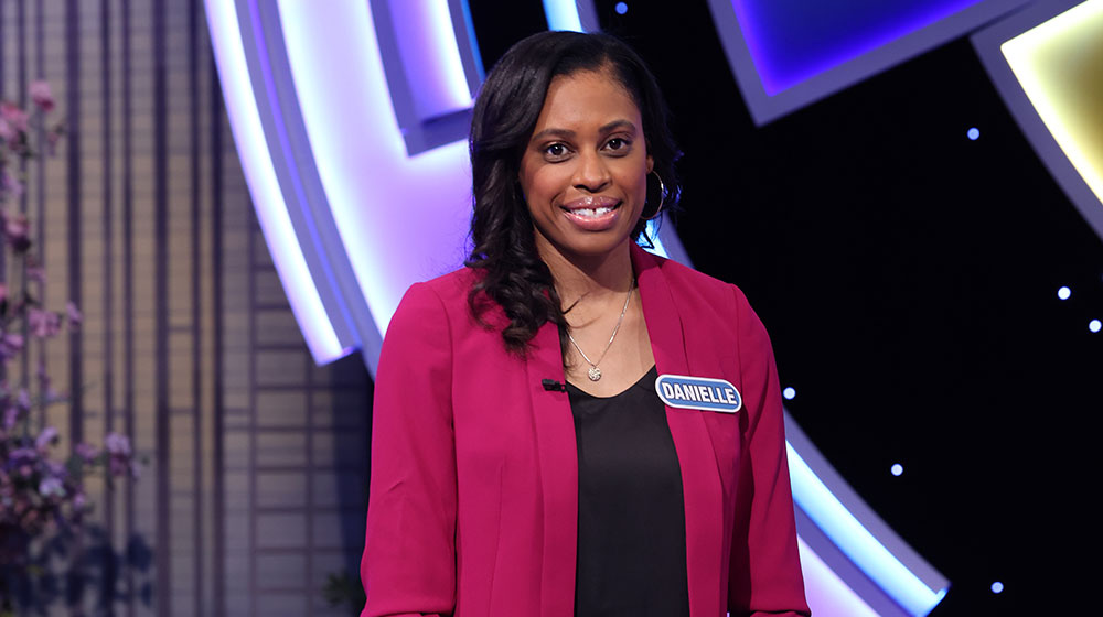 Danielle Booker standing behind the wheel on the Wheel of Fortune set Danielle Booker standing behind the wheel on the Wheel of Fortune set