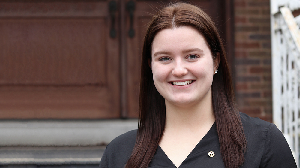 Delta Sigma Pi member Sarah Hoffman smiles outside.