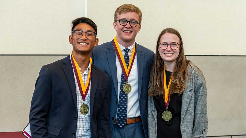 Three students with medals around their necks Three students with medals around their necks