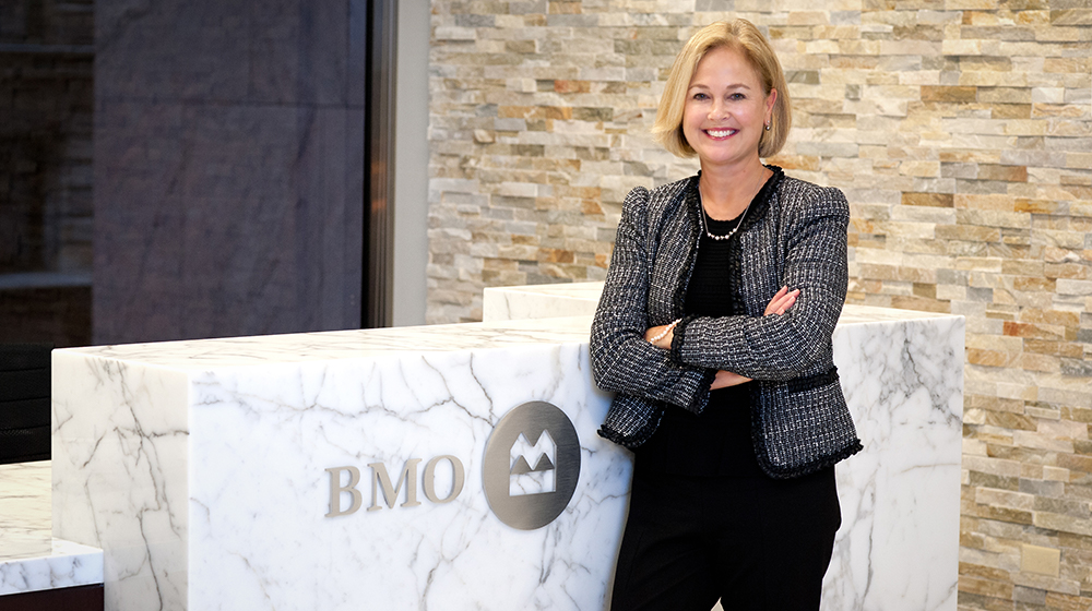 Professional woman standing next to BMO Harris desk.