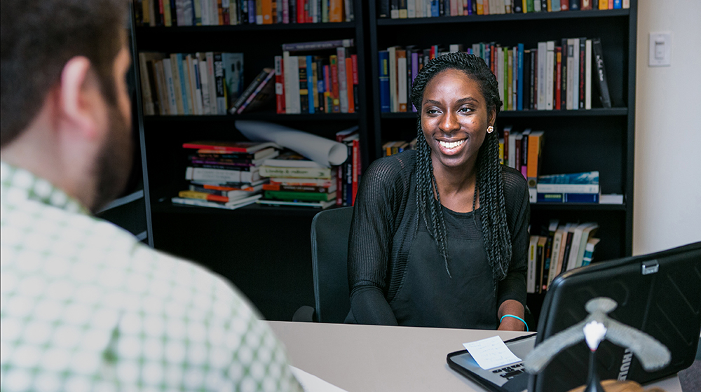 Image of a woman in front of a bookcase talking to a man