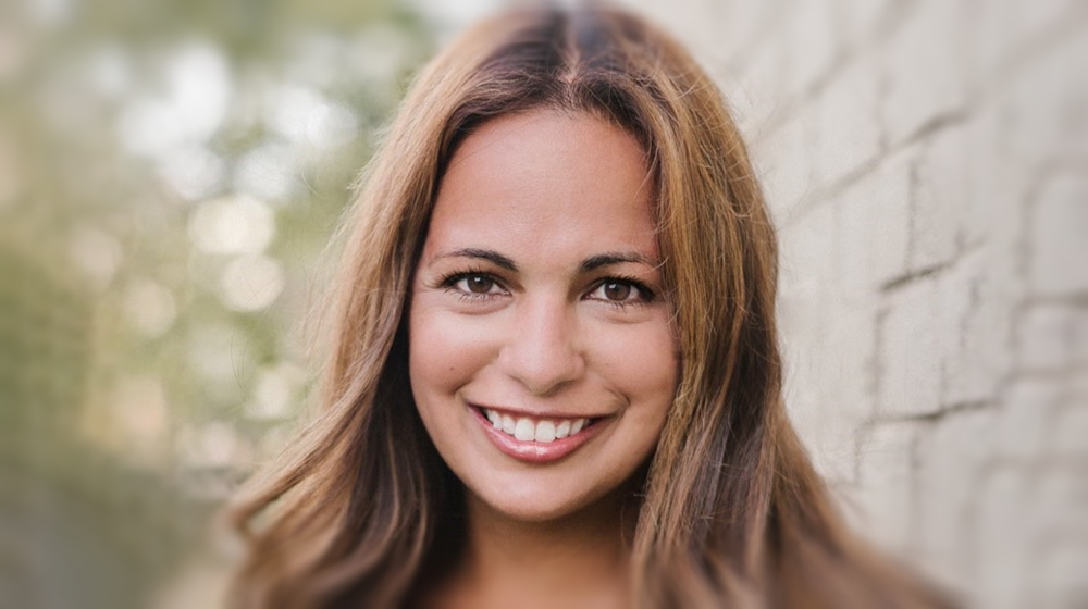 Headshot of Rocky Belmonte outside by a brick wall and trees