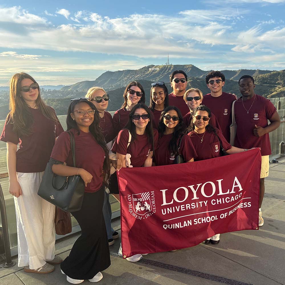 Quinlan students hold a Quinlan flag on a hillside overlooking the Hollywood sign.