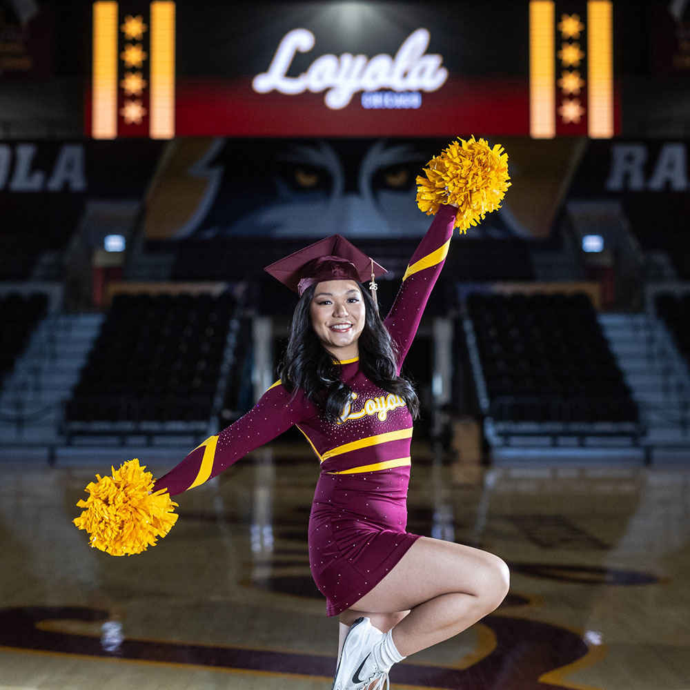 Rianne Fujinaga in a Loyola Dance Team unifrom and graduation cap posing at Gentile Arena