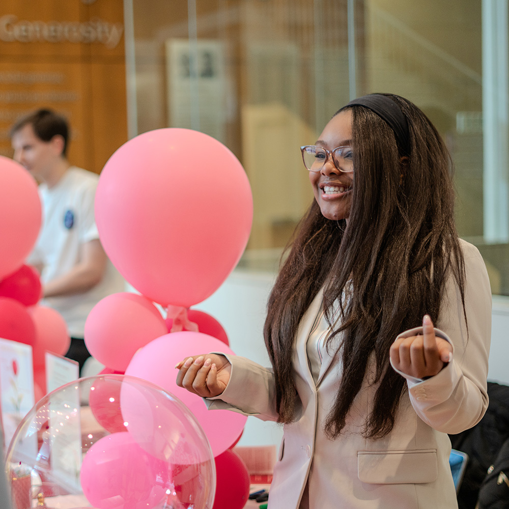 A student shows off her side hustles with pink balloons