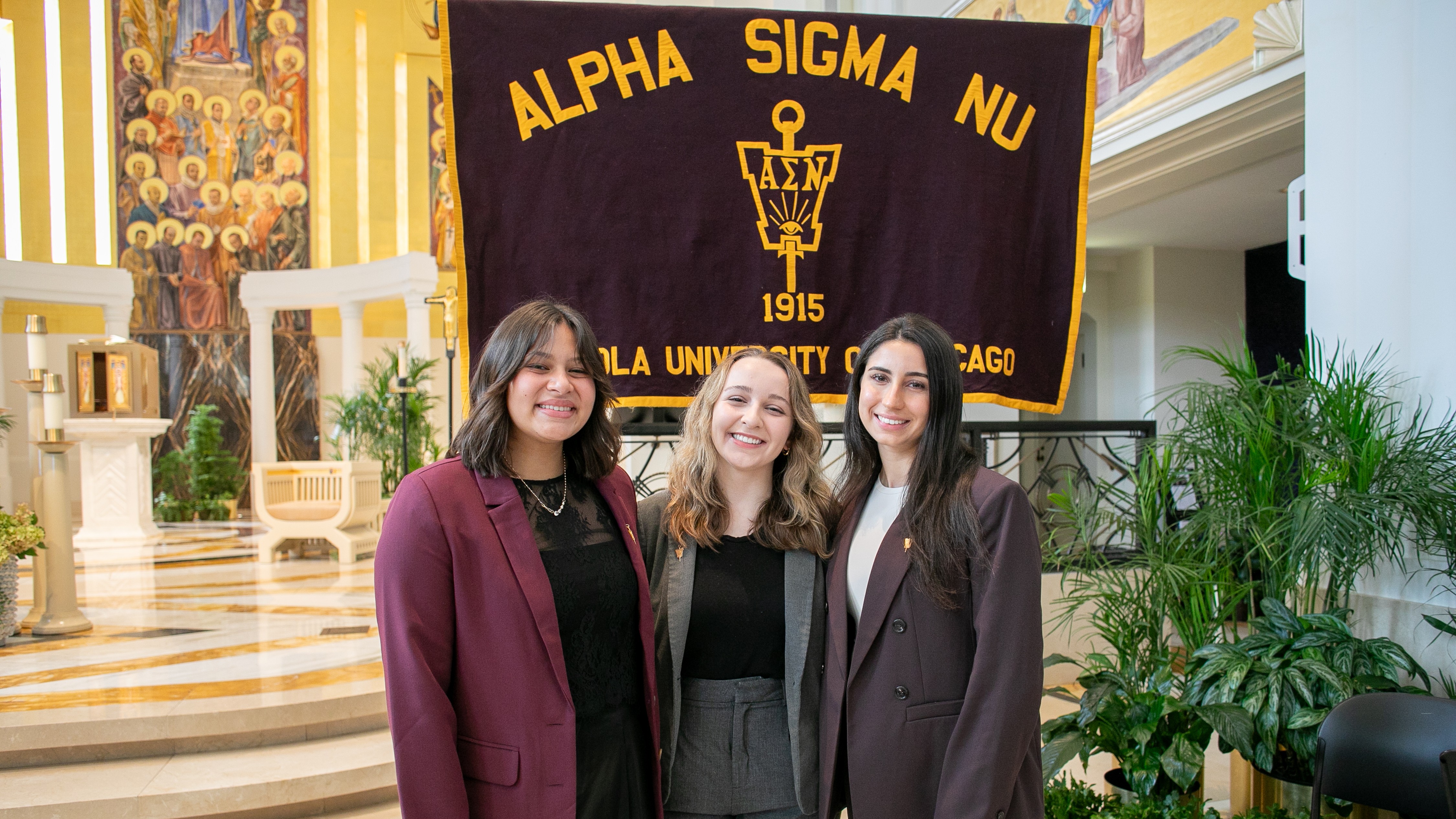 Three ASN chapter officers in front of ASN's maroon and gold banner