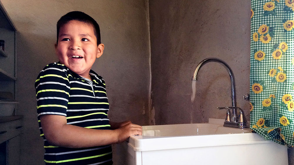 A young boy at a sink, a beneficiary of DIGDEEP, a company founded by Loyola University Chicago alum George McGraw that builds wells and set up water delivery systems where there are deficient systems or none at all