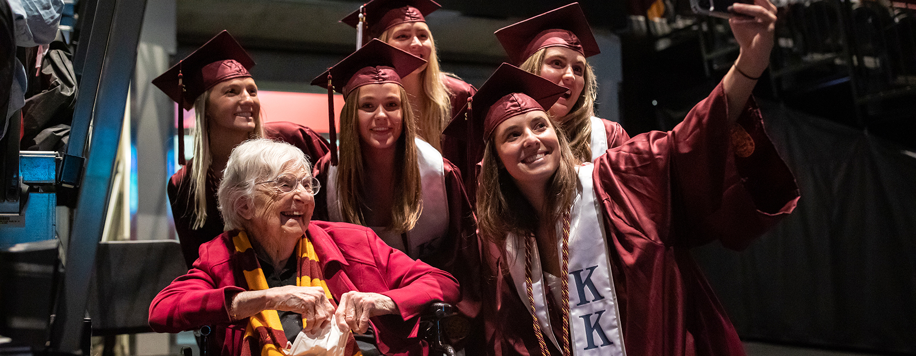 Sister Jean smiles as she sits with a group of SCPS graduates.