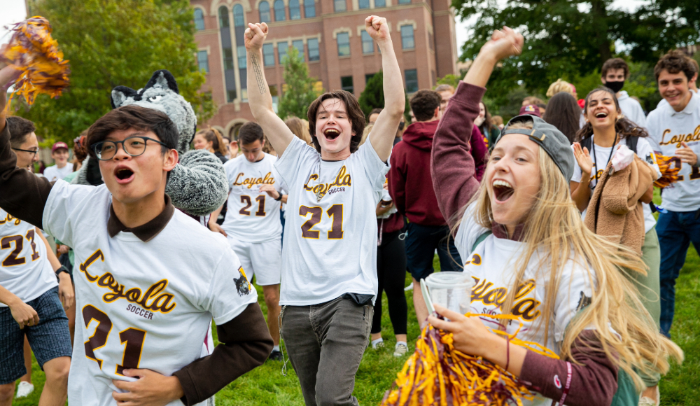 A group of people cheering and celebrating with pom-poms in front of a building.