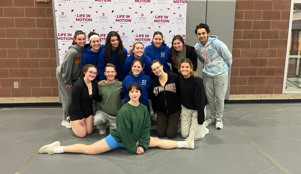 A group of young adults pose for a photo in front of a 