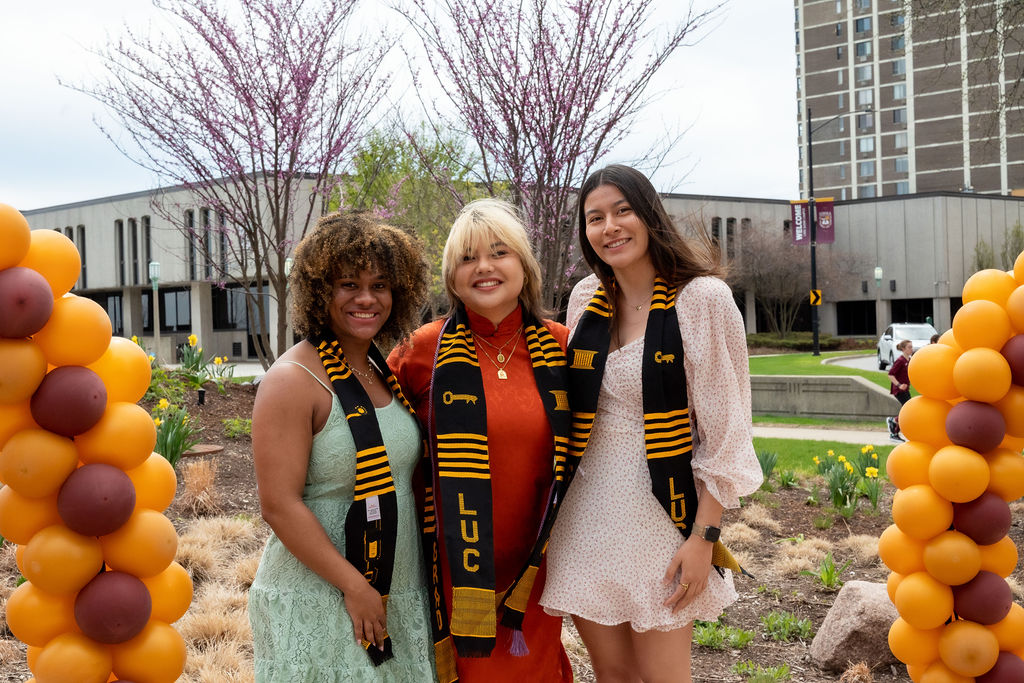 Students wearing stoles from the Legacy Celebration pose with a balloon backdrop at the reception at Piper Plaza.