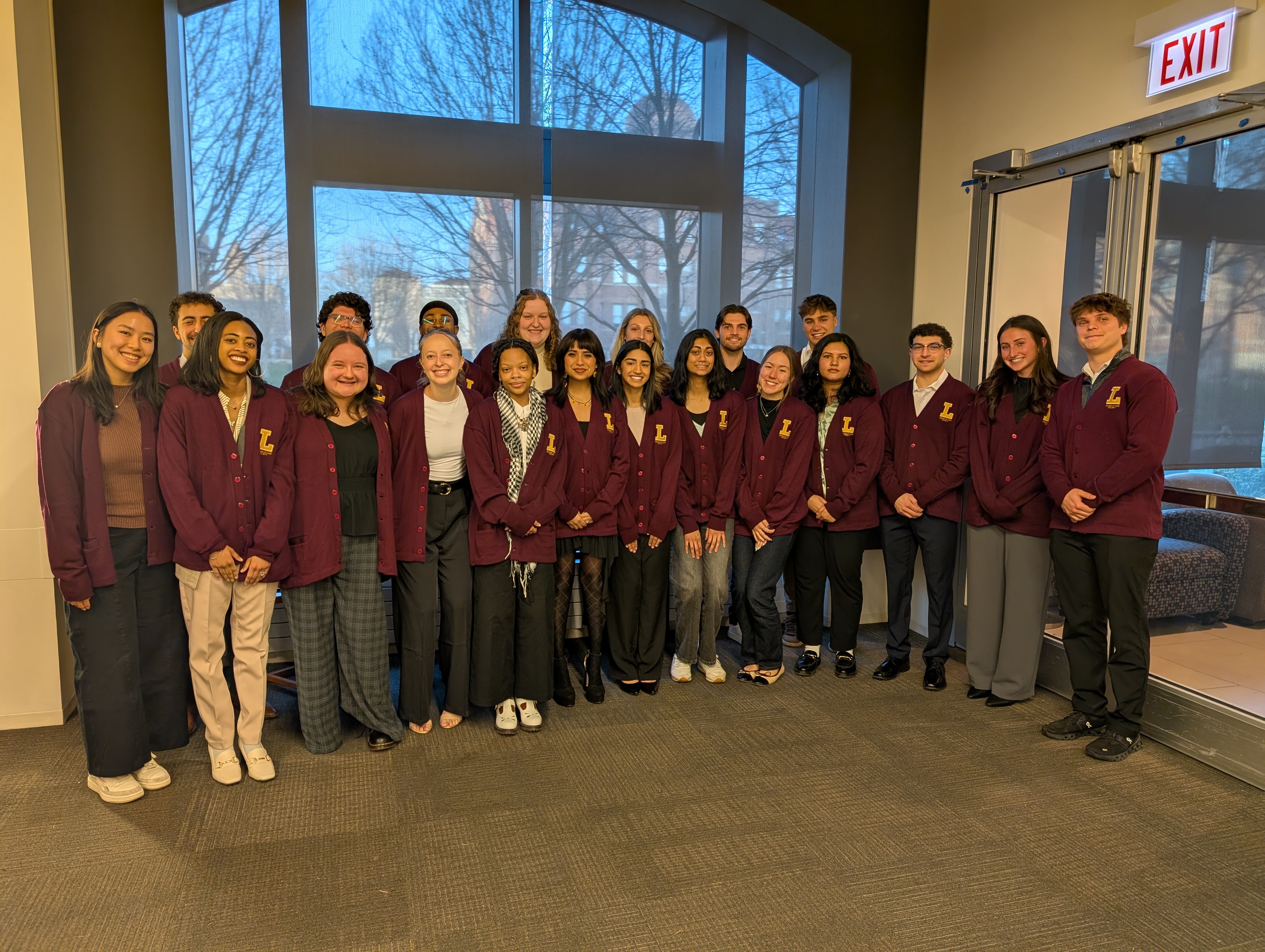 Group of students wearing matching Loyola cardigans posing together indoors.